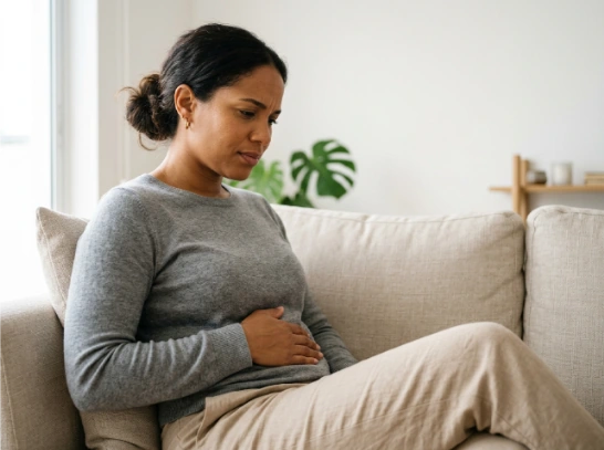 Mujer en casa con una mano sobre su abdomen